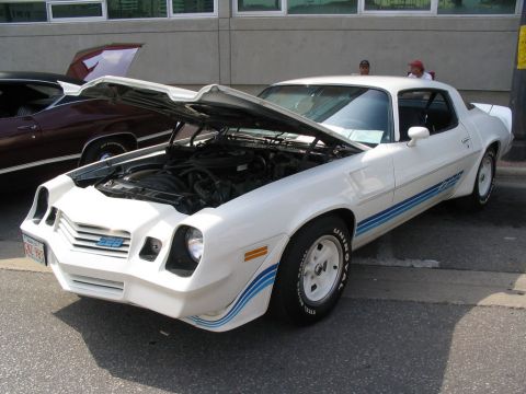 1993 Ford Taurus - A white coupe with blue racing stripes and its hood open, displaying the engine. A 'Z28' badge is visible on the front grille.