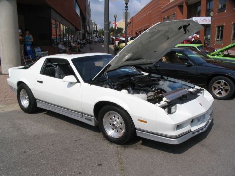 1993 Ford Taurus - A white Chevrolet Camaro is displayed with its hood open, revealing the engine compartment.