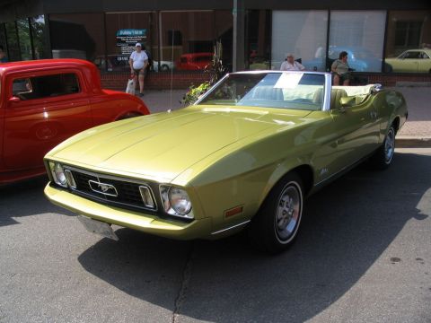 1993 Ford Taurus - A classic convertible is displayed at an outdoor car show, parked beside a red coupe.