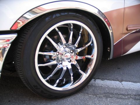 1993 Ford Taurus - A close-up view of a car's wheel and fender trim, showing custom chrome accents and two-tone paint.