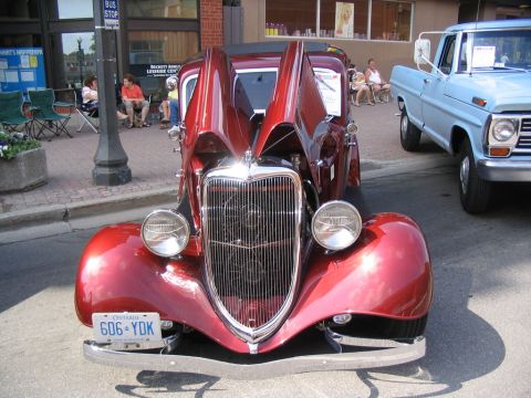 1993 Ford Taurus - A vintage red Ford hot rod is displayed with its hood open next to a blue Ford pickup truck.