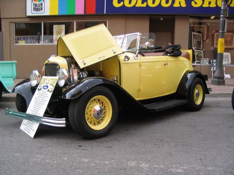 1993 Ford Taurus - A classic yellow Ford Roadster is displayed with its hood open, showing the engine compartment.
