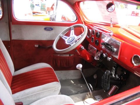 1993 Ford Taurus - The interior of a custom red vehicle features plush seating, a chrome steering wheel, and a detailed dashboard with multiple gauges.