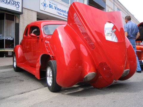 1993 Ford Taurus - A bright red custom hot rod is displayed with its hood open, revealing intricate details.