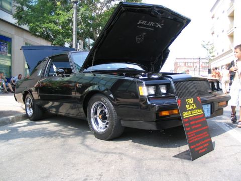 1993 Ford Taurus - A black 1987 Buick Grand National is displayed with its hood open, a sign with vehicle details.