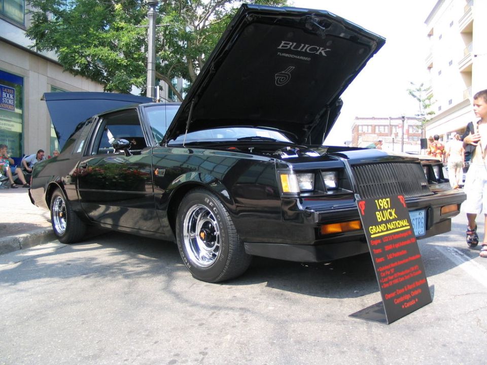Black 1987 Buick Grand National with hood open, showing a display sign