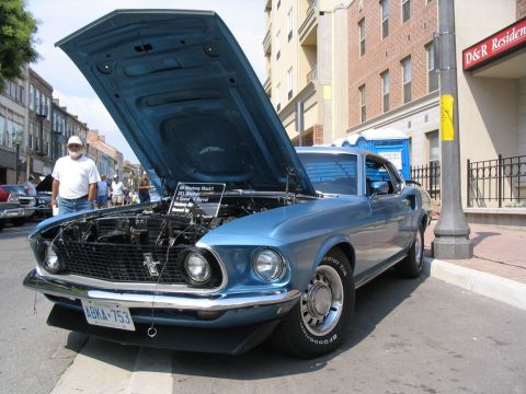 1993 Ford Taurus - A blue 1969 Ford Mustang Mach 1 is displayed with its hood open at a car show.