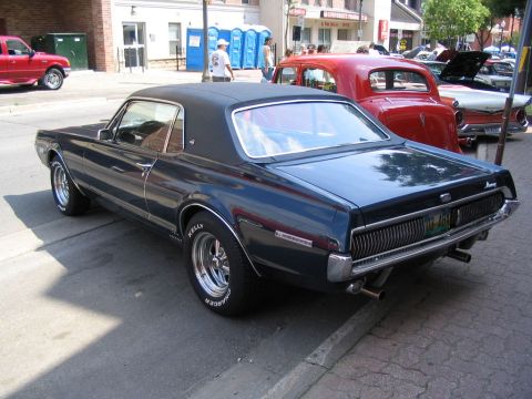 1993 Ford Taurus - Dark blue 1969 Mercury Cougar XR-7 parked on street with other vehicles and buildings.