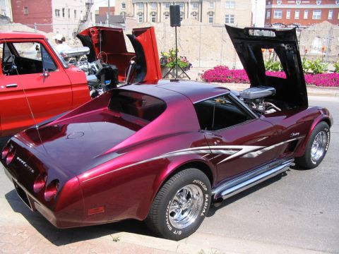 1993 Ford Taurus - A custom Corvette Stingray is displayed at a car show next to a red pickup truck, both with their hoods open.