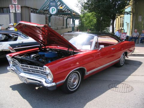 1993 Ford Taurus - A red classic car, likely a 1967 model, is displayed with its hood open at an outdoor event.