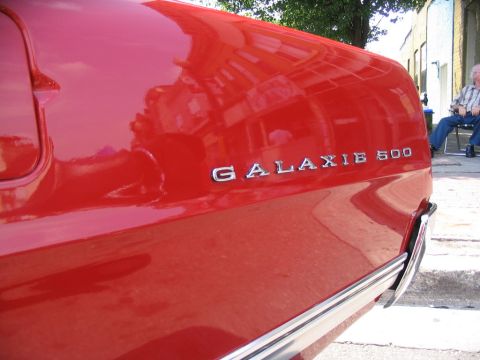 1993 Ford Taurus - The chrome emblem on the side of a red car reads "GALAXIE 500".