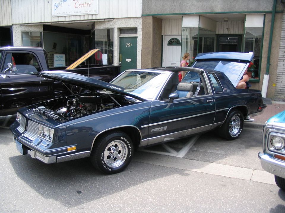 Dark blue coupe with hood and trunk open, chrome wheels, silver trim