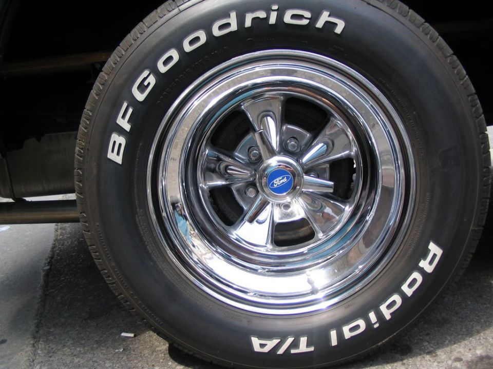 Close-up of a BFGoodrich Radial T/A tire on a chrome 5-spoke wheel with a blue Ford center cap