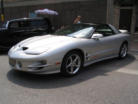 1993 Ford Taurus - Silver Pontiac Firebird Trans Am parked on a street, with a black sedan behind it.