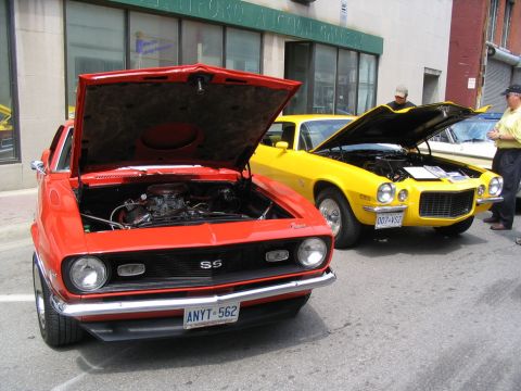 1993 Ford Taurus - Two classic Camaros are displayed with their engines exposed at an outdoor car show.