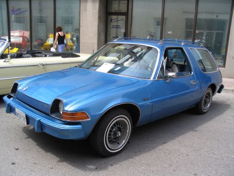 1993 Ford Taurus - A blue AMC Pacer wagon is parked at a car show next to a convertible.