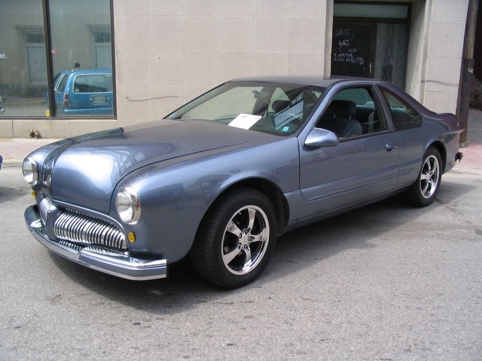 Blue custom car with a chrome grille and headlights reminiscent of older vehicles