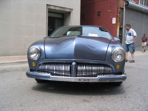 1993 Ford Taurus - A blue car with a distinctive chrome grille is parked on a city street, with two men standing nearby.