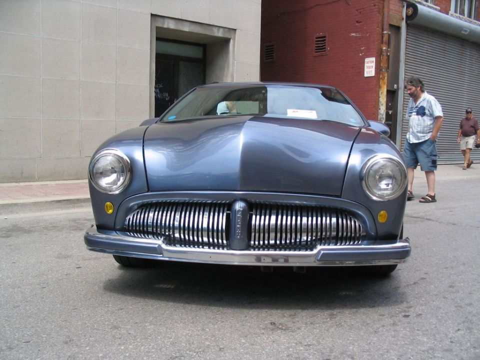 blue car with large chrome grille and round headlights parked on street