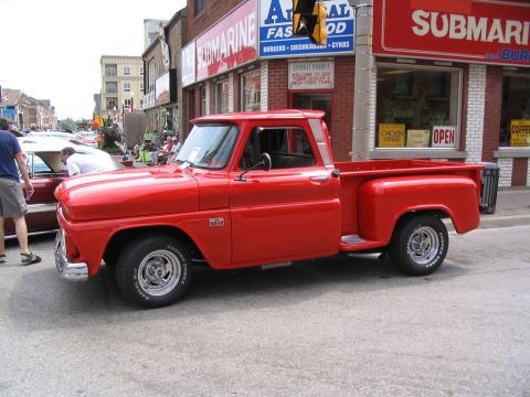 1993 Ford Taurus - A red pickup truck is parked on a street with buildings in the background.