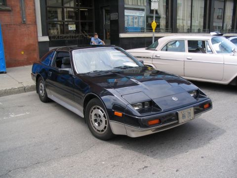 1993 Ford Taurus - A black Nissan 300ZX is parked on a city street next to a vintage cream-colored sedan.