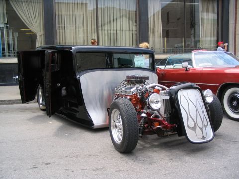 1993 Ford Taurus - A custom hot rod with its doors open sits next to a red convertible at a car show.