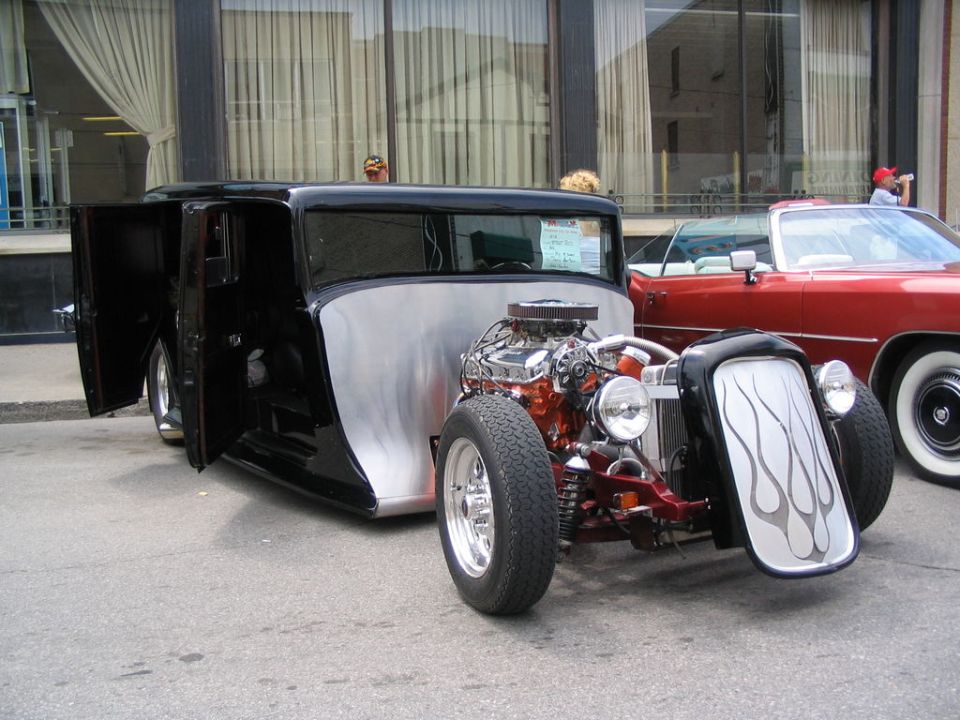 Black hot rod with exposed engine, silver flame decals on the grille, and doors open