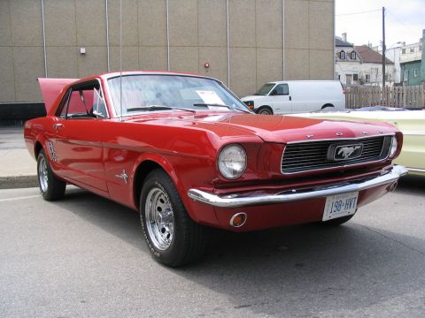 1993 Ford Taurus - This red 1965 Ford Mustang coupe is displayed with its hood open at a car show.