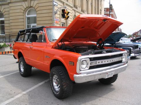 1993 Ford Taurus - A vintage orange Chevrolet K5 Blazer is displayed with its hood open at an outdoor car show.