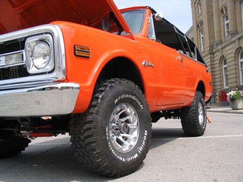 1993 Ford Taurus - This lifted orange SUV features BFGoodrich Mud-Terrain tires and a prominent chrome bumper, seen at a car show.