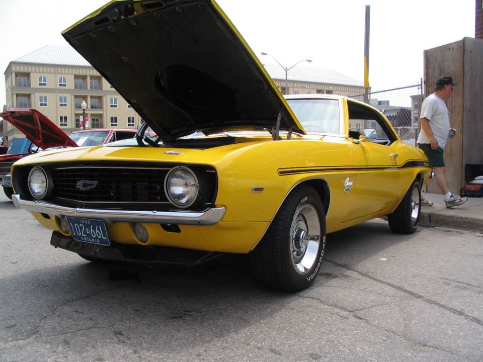 Yellow 1969 Chevrolet Camaro, front 3/4 view, hood open. License plate reads 102-66L