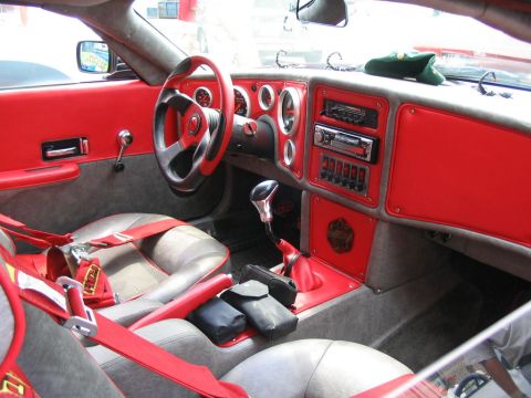 1993 Ford Taurus - The interior features custom red and gray upholstery, racing harnesses, and an aftermarket stereo system.