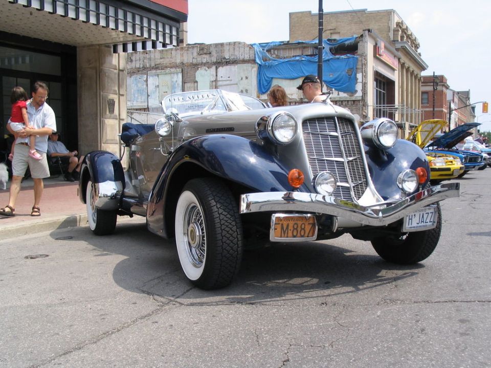 Front view of a two-tone blue and silver vintage convertible with whitewall tires parked on a street