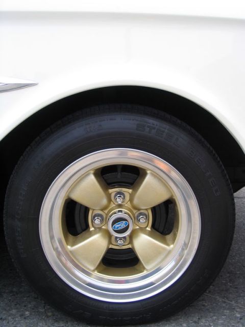 1993 Ford Taurus - Close-up of a gold five-spoke wheel with a Ford logo, mounted on a white vehicle.