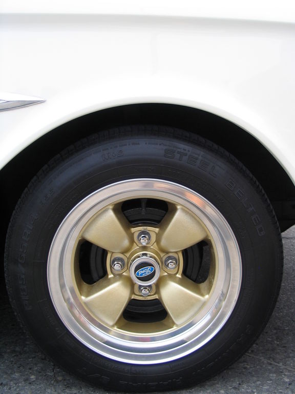 Gold five-spoke wheel with Ford logo on white car