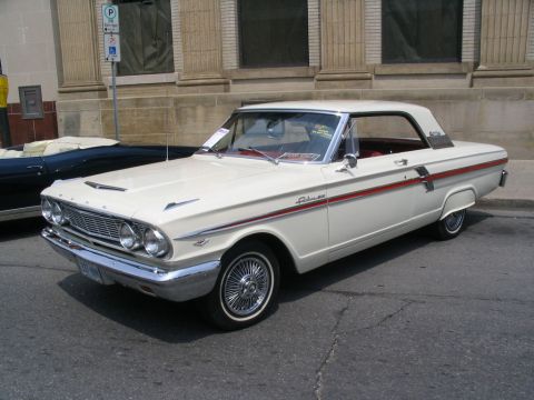 1993 Ford Taurus - White 1962 Ford Galaxie 500 with red side trim parked on street next to a dark convertible.