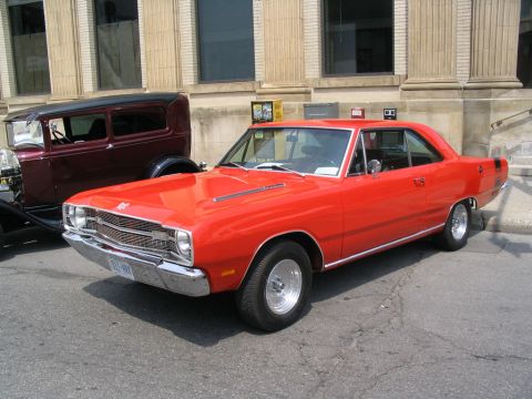 1993 Ford Taurus - A classic red Dodge Dart is parked on the street next to another vintage vehicle.