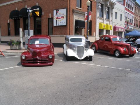 1993 Ford Taurus - A street scene with three vintage automobiles on display at a car show.
