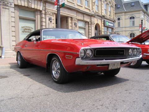 1993 Ford Taurus - A red 1970 Dodge Challenger is displayed at a car show, with another vehicle visible behind it.