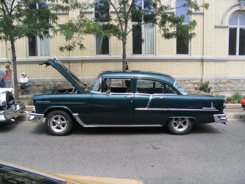 1993 Ford Taurus - Side view of a dark green 1955 Chevrolet Bel Air sedan with its hood open at a car show.