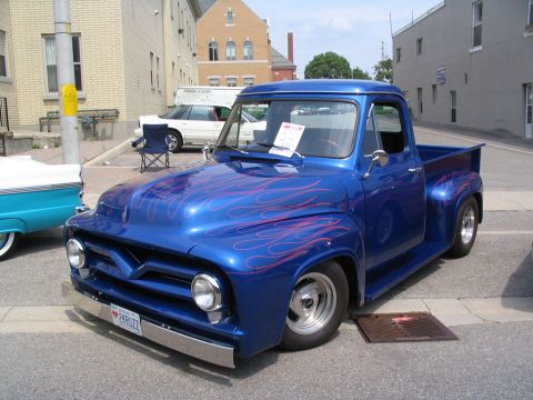1993 Ford Taurus - A classic blue Ford pickup truck with custom flame graphics is displayed at an outdoor event.