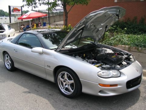 1993 Ford Taurus - A silver Chevrolet Camaro SS is parked with its hood open, revealing the engine compartment.