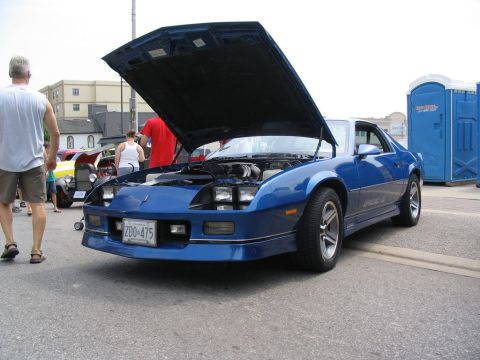 1993 Ford Taurus - A blue Chevrolet Camaro from the 1980s is displayed with its hood open at a car show.