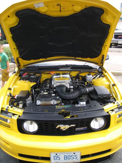 1993 Ford Taurus - Yellow Ford Mustang's engine bay is on full display at a car show.