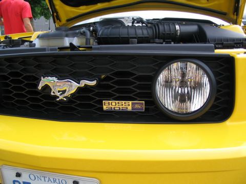 1993 Ford Taurus - Front view of a yellow Ford Mustang Boss 302, its distinctive grille, running horse emblem, and 'BOSS 302' badging.