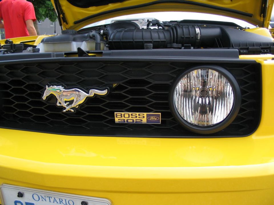 Yellow Ford Mustang Boss 302 grille with running horse emblem and 'BOSS 302' badge
