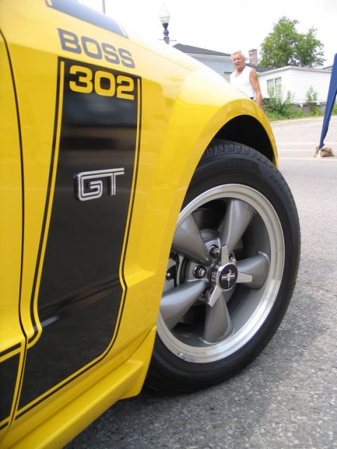 1993 Ford Taurus - A yellow Ford Mustang Boss 302 GT is shown from the front quarter panel to the wheel.