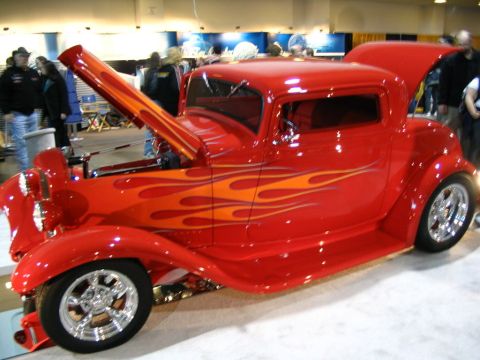 1993 Ford Taurus - A custom red hot rod with flame graphics is displayed with its hood and trunk open.