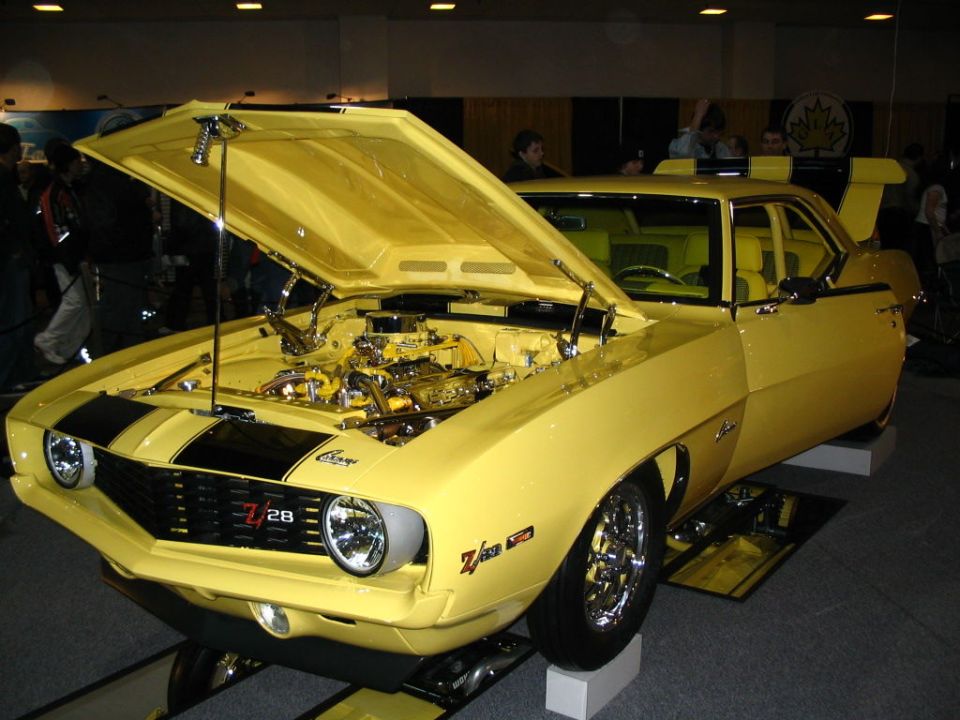 Yellow 1969 Chevrolet Camaro Z28 with black stripes, hood open revealing engine