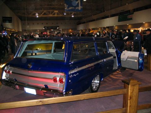 1993 Ford Taurus - A custom blue station wagon is displayed indoors with its doors open, attracting attention from onlookers.